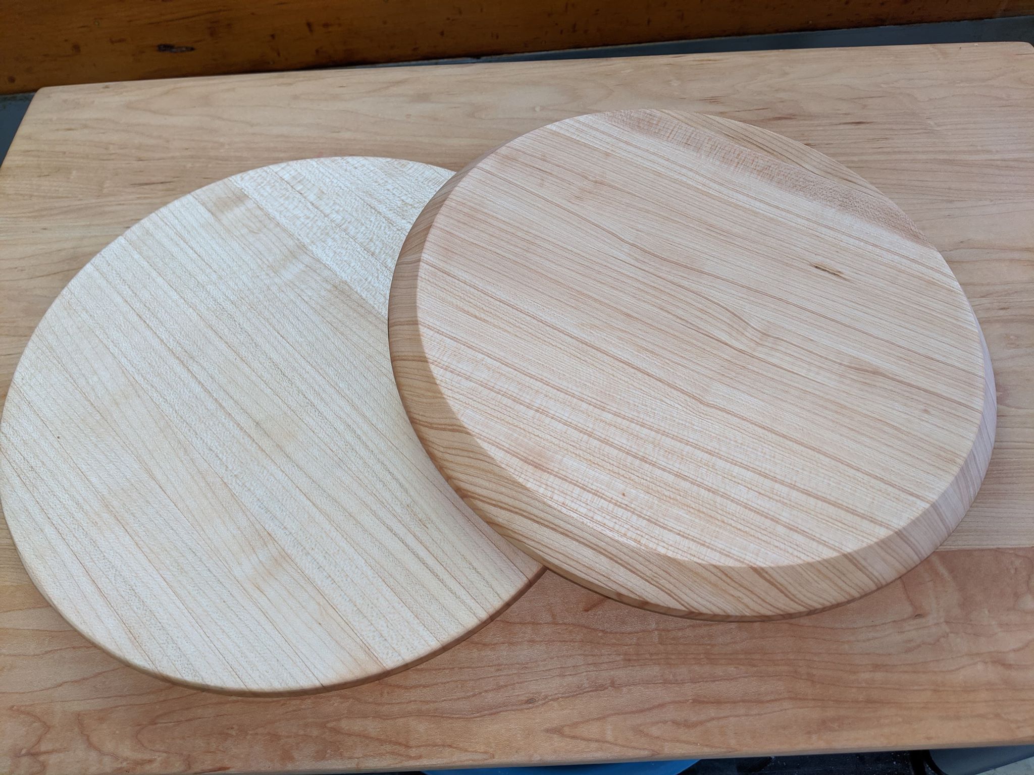 Two round maple Portage Pie rolling boards on a workbench