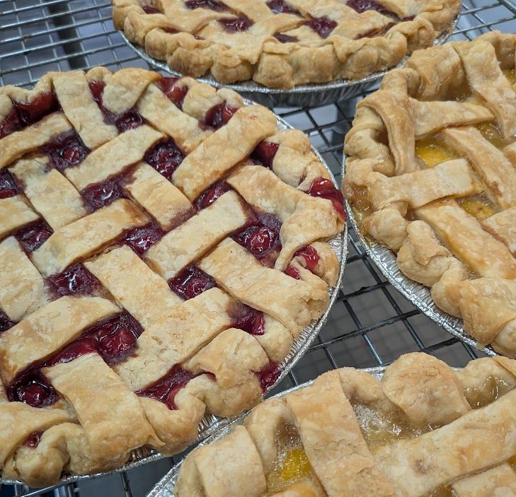 Fresh lattice-top cherry and peach pies cooling on a rack